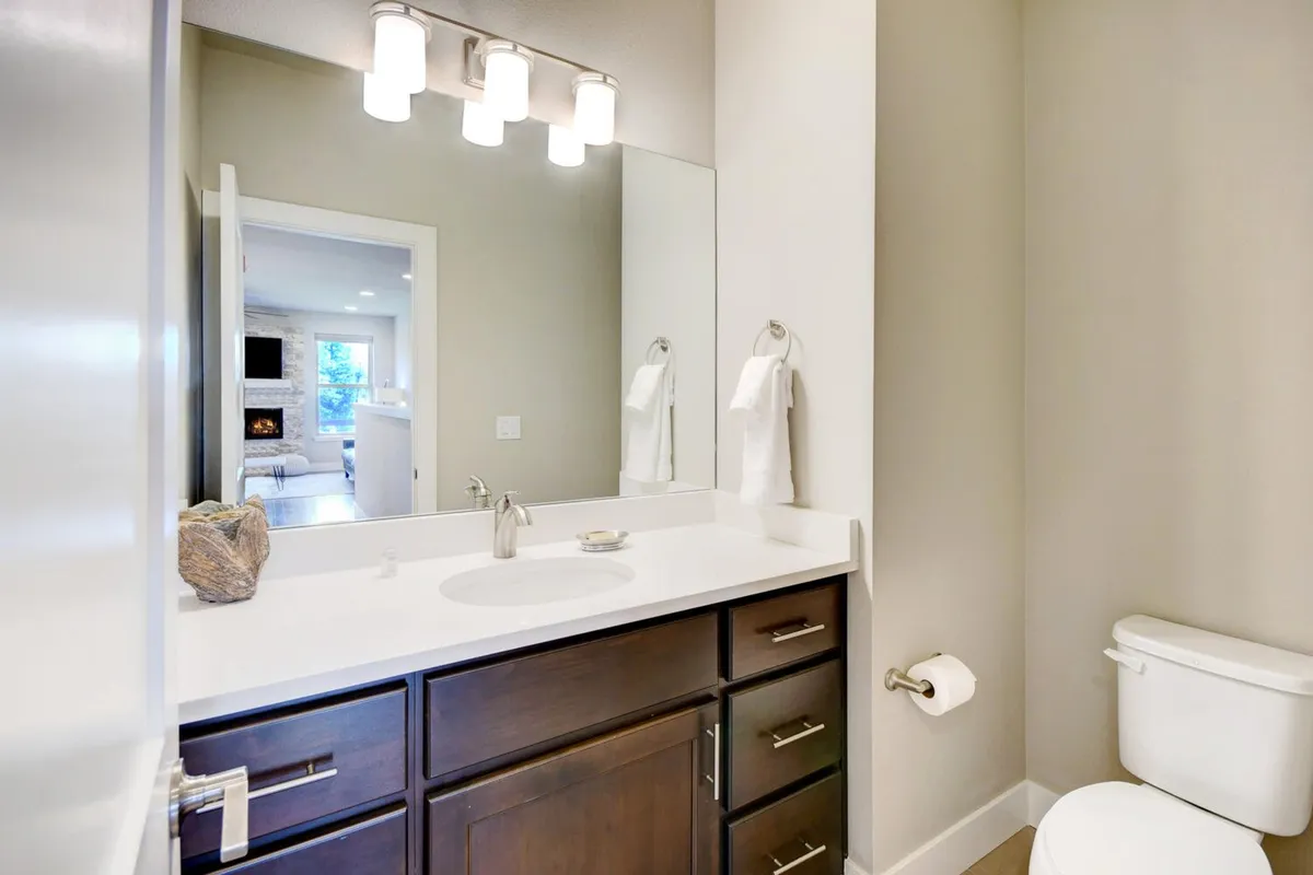 A modern bathroom with a sleek vanity, a large mirror, elegant light fixtures, and neatly arranged toiletries. The setting is fresh and inviting, suggesting a space designed for relaxation and self-care.